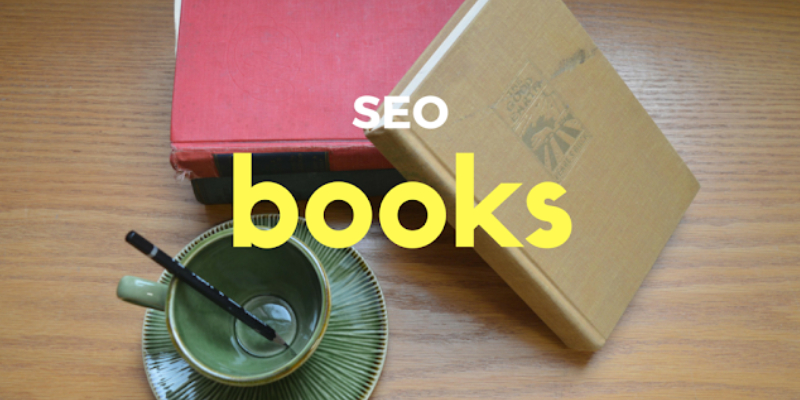 Two Books About SEO Which Is Placed On The Wooden Deck Table With A Cup And Saucer.