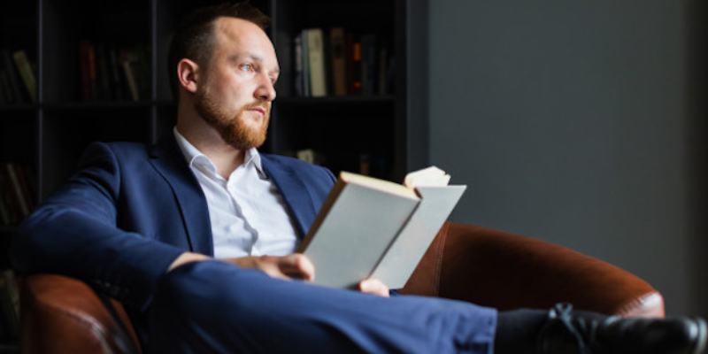 An Entrepreneur Reading A Book About Entrepreneurship Skills.