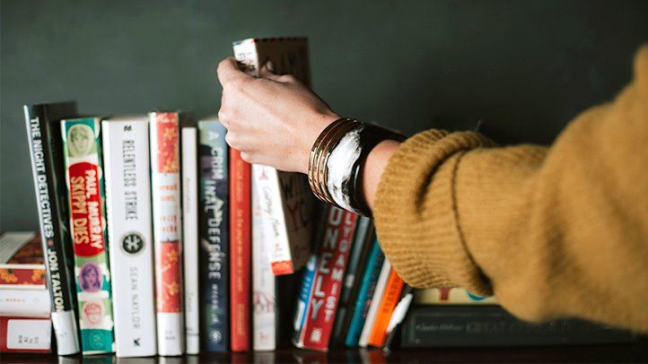 A Lady Taking A Book From The Book Stack Of Entrepreneurs.