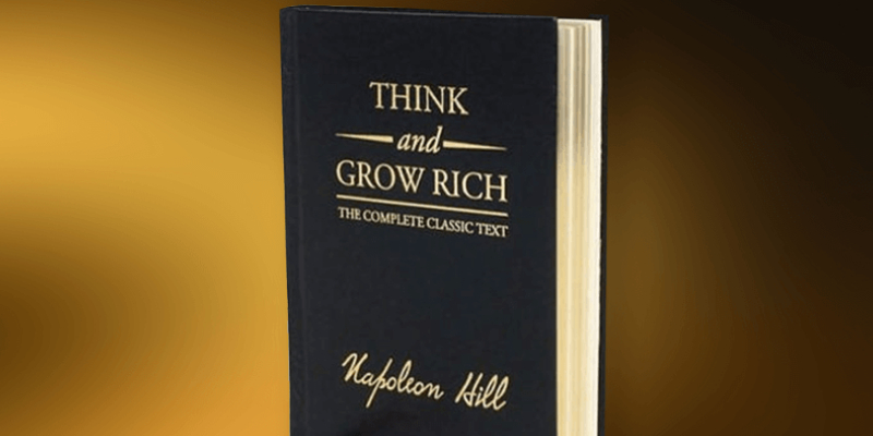 Think And Grow Rich - A Book By Napolion Hill On Display In A Brown Background.