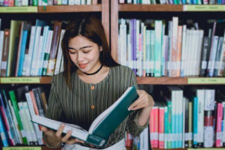 A Young Lady Opened And Read A Book In A Library.