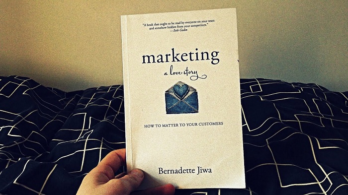 A Person Holding A Marketing Book On Her Hand.